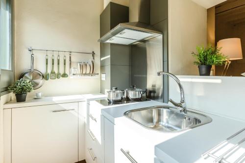 a white kitchen with a sink and a stove at Flateli Ballesteries in Girona