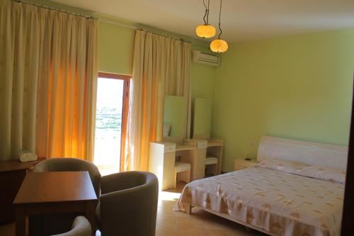 Schlafzimmer mit einem Bett, einem Schreibtisch und einem Fenster in der Unterkunft Alen Bar Hotel in Tirana