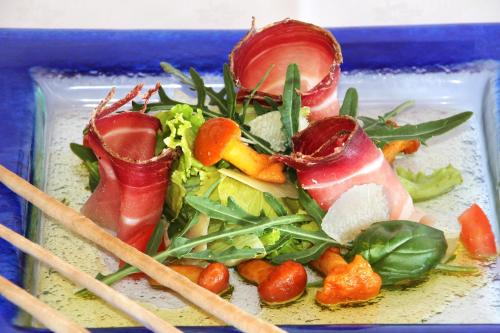 a plate of food with meat and vegetables with chopsticks at Panoramahotel Obkircher in Nova Ponente