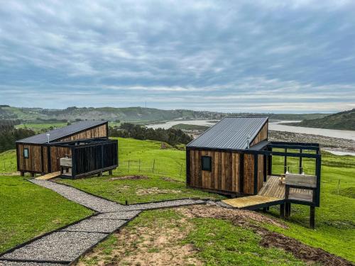 two wooden cabins on a hill with a bench at Rio Arriba Ecoloft in El Culenar