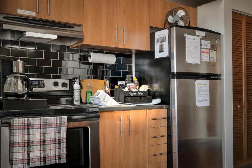 a kitchen with a stainless steel refrigerator and wooden cabinets at Beautiful APARTMENT - GORGEOUS VIEW of the city - 7 MINUTE WALK TO METRO - SELF CHECK IN in Montréal