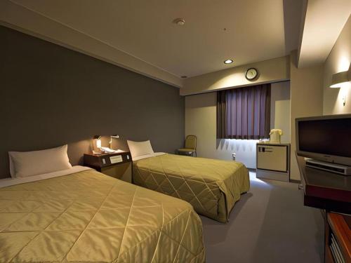 a hotel room with two beds and a flat screen tv at Shizuoka UI Hotel in Shizuoka