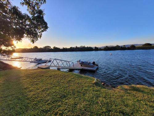 Ein Boot liegt an einem Dock auf einem See. in der Unterkunft Tweed River Waterfront Cottage in Murwillumbah