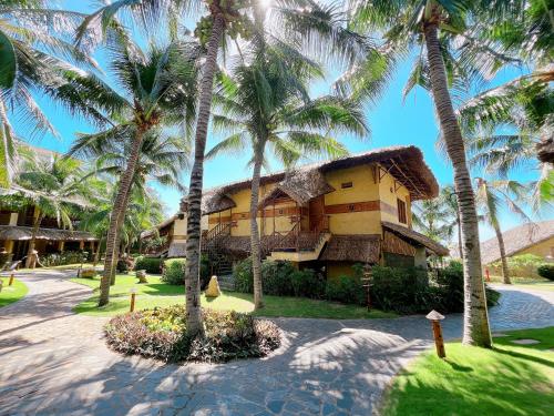 un bâtiment avec des palmiers devant dans l'établissement Aroma Beach Resort and Spa, à Mui Ne