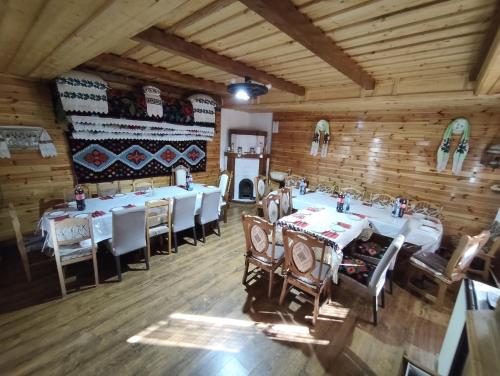 a dining room with white tables and chairs and wooden walls at Casa Utan in Văleni