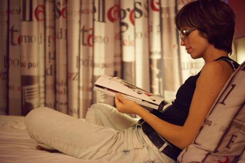 a woman sitting on a bed reading a book at Ace Hotel Montluçon in Saint-Victor