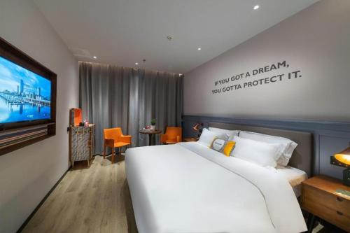 a bedroom with a large white bed and a tv at City Comfort Premier Hotel Xiaogan Anlu Railway Station Dongda Times Square in Teianfu