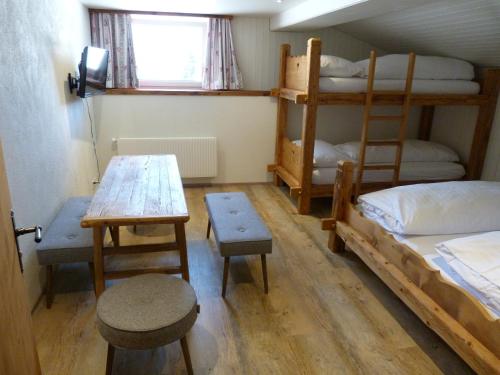 a room with bunk beds and a table and a desk at Berglodge Ristis in Engelberg