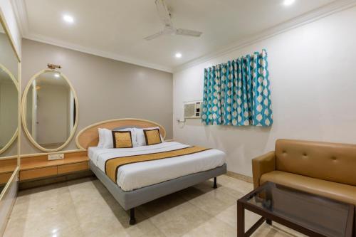 a bedroom with a bed and a chair and a mirror at Hotel Stay Land Inn Versova in Mumbai