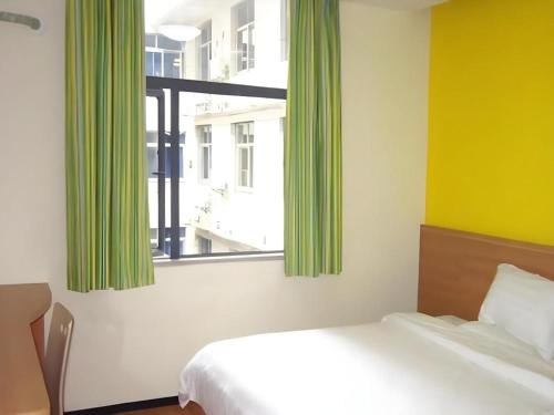 - une chambre avec un lit et une fenêtre avec des rideaux verts dans l'établissement 7 Days Inn Jinggangshan Scenic Spot, à Jinggangshanzonghekenzhichang