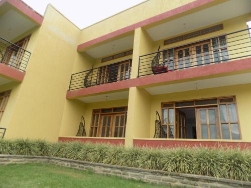 a yellow building with balconies and plants at Fort Fun City Hotel Fort Portal in Fort Portal
