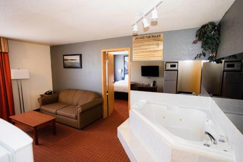 a hotel room with a tub and a bedroom at Super 8 by Wyndham Drayton Valley in Drayton Valley