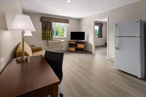 a living room with a white refrigerator and a table at Super 8 by Wyndham Latham - Albany Airport in Latham