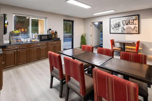 a dining room with a table and red chairs at Super 8 by Wyndham Latham - Albany Airport in Latham