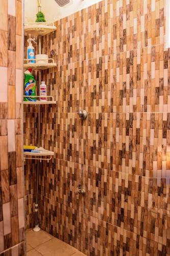 a bathroom with a shower with a tile wall at Velora Suites Kilifi in Kilifi