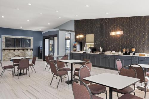 a restaurant with tables and chairs and a kitchen at Super 8 by Wyndham Fort Wayne in Fort Wayne