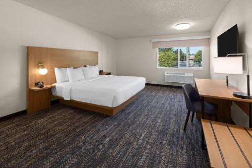 a hotel room with a bed and a desk at Ramada by Wyndham Merced in Merced