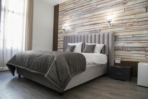 ein Schlafzimmer mit einem großen Bett und einer Holzwand in der Unterkunft Corner House in Lowetsch