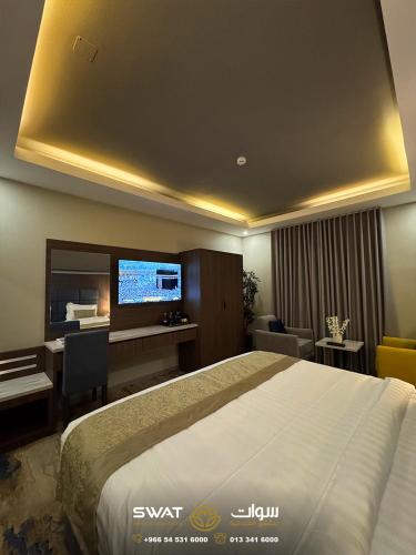 a bedroom with a bed and a desk and a tv at سوات للشقق المخدومة 5 in Al Khobar