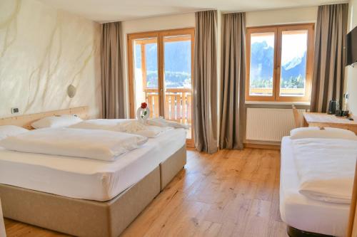 een slaapkamer met twee bedden en een groot raam bij Hotel Savoia in Dobbiaco