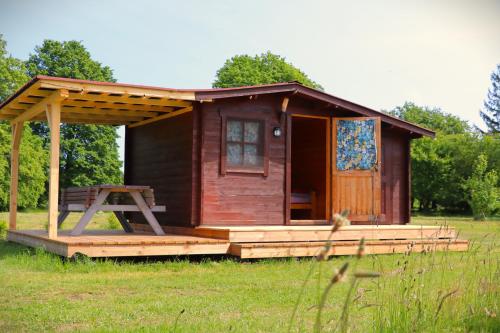 a small wooden cabin with a porch in a field at SP camping Spāres Prieduļi in Nīca