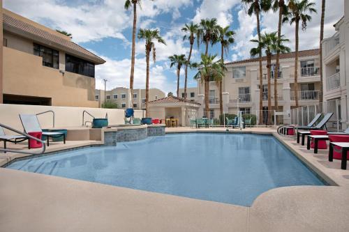 a large swimming pool with chairs and palm trees at Home2 Suites by Hilton Scottsdale Old Town in Scottsdale