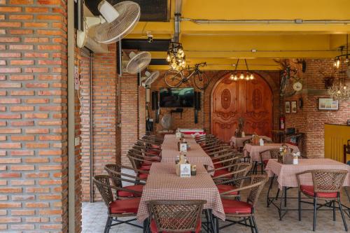 a dining room with tables and chairs and a brick wall at Pongphen Guesthouse - SHA Plus Certified in Kanchanaburi City