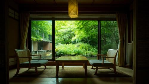 Una habitación con dos sillas y una mesa y una ventana grande. en Oku Yugawara Tsubaki, en Yugawara