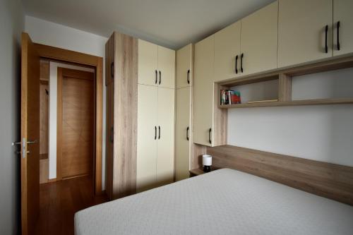 a bedroom with white cabinets and a white bed at Panorama Studio in Novi Sad