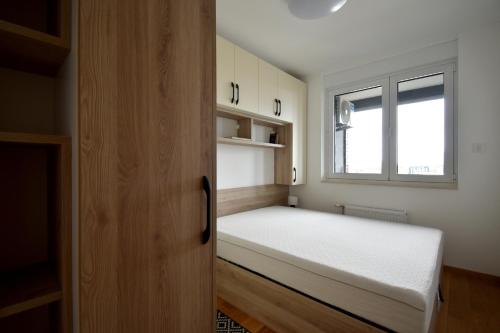 a small bedroom with a bed and a window at Panorama Studio in Novi Sad