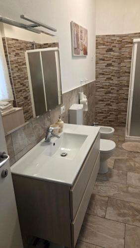 a bathroom with a sink and a toilet and a mirror at Rocca view central flat in Arona