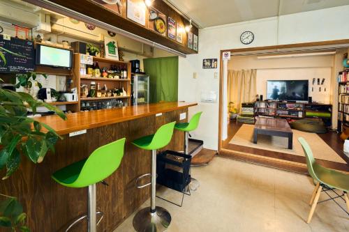 a bar with green bar stools and a living room at Green Guesthouse in Kagoshima