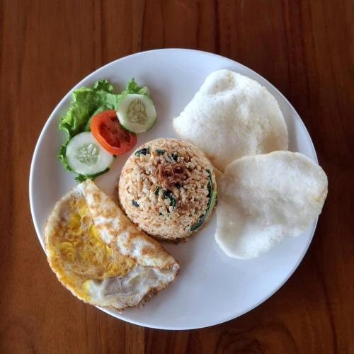 un plato de comida con huevos y pan y verduras en Berkat Surya Dewa Guest House, en Benuaanyar