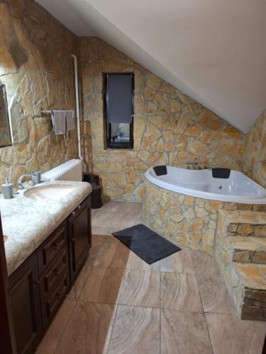 a stone bathroom with a tub and a sink at Szelek Palotája in Écs