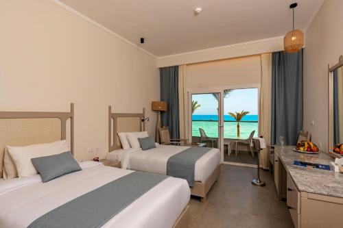 two beds in a hotel room with a view of the ocean at Sunny Days El Palacio Resort & Spa in Hurghada