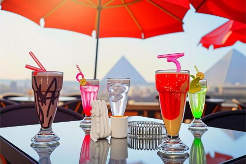 a table with four different colored drinks on it at Pyramids & SphinX Hut HoteL in Cairo