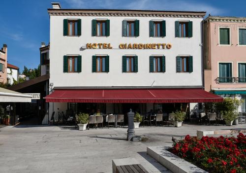 a hotel greenhouse with a red awning in front of a building at Hotel Giardinetto Venezia in Venice-Lido