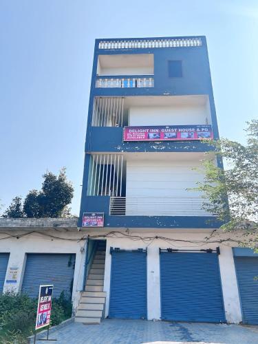 a tall blue building with two garage doors and a sign at Delight Inn Guest House & PG in Lālewāl