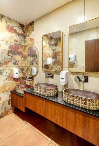 two sinks in a bathroom with two mirrors at PASSIONS HOTEL EDATHUA - Alappuzha in Champakulam