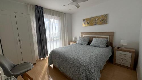 カンデラリアにあるAPARTAMENTO Ocean Elevenのベッドと椅子と窓のある寝室