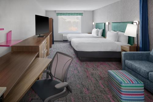 a hotel room with two beds and a tv and a couch at Home2 Suites By Hilton Frankenmuth in Frankenmuth