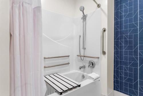 a bathroom with a tub and a shower with a sink at Spark by Hilton Essex Junction Burlington in Essex Junction