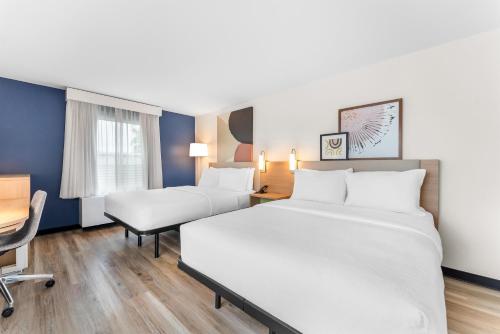 a hotel room with two beds and a desk at Spark by Hilton Essex Junction Burlington in Essex Junction