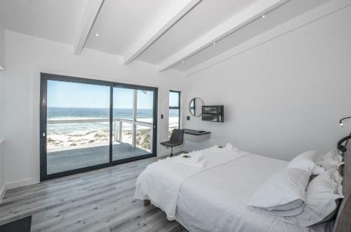 a bedroom with a bed and a view of the ocean at Sandbanks Villa in Yzerfontein