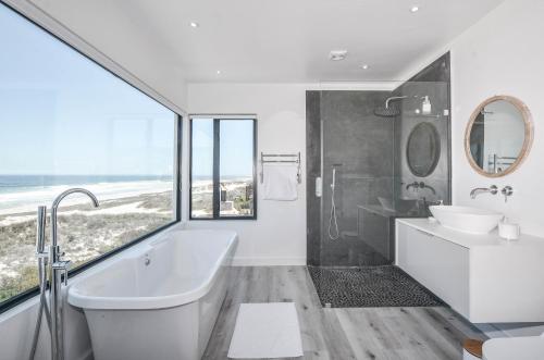 a white bathroom with a tub and a sink at Sandbanks Villa in Yzerfontein