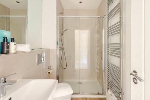 ein weißes Badezimmer mit Dusche und Waschbecken in der Unterkunft Spacious 4-BR House in Oxfordshire with Free Parking and Wi-Fi in Long Hanborough