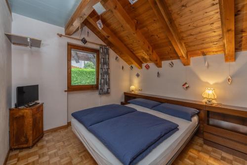 Schlafzimmer mit einem Bett mit blauer Bettwäsche und einem TV in der Unterkunft Romantic Hideaway with Mountain View and Hiking Trails in Terzels
