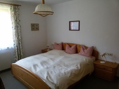 a bedroom with a bed with white sheets and pink pillows at Ferienwohnung Heidi in Flachau