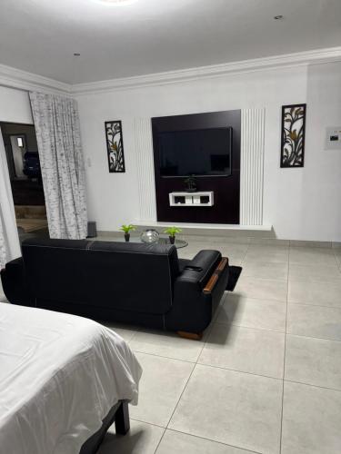 een woonkamer met een zwarte bank en een tv bij WeMvula Guesthouse in Mtubatuba