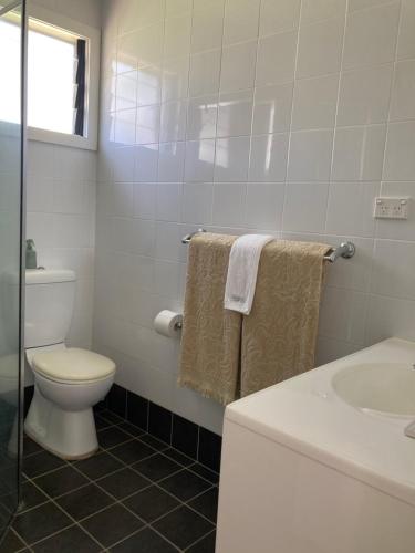 a white bathroom with a toilet and a sink at Riverview Cottage in Dunbogan